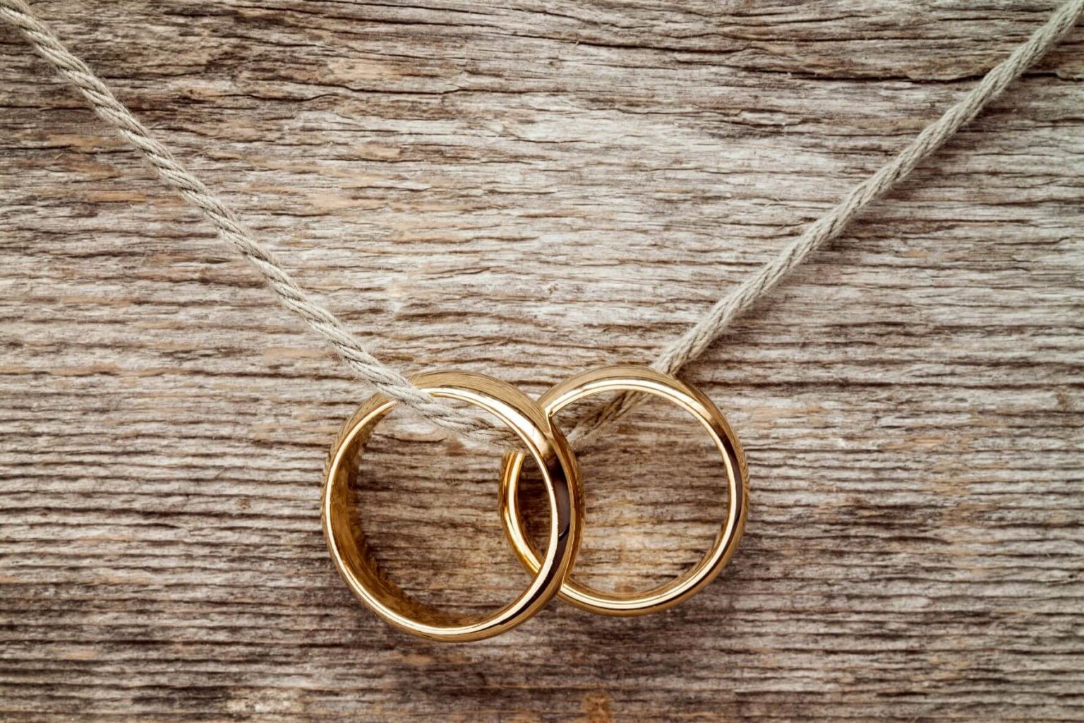 Rings & Jewellery 23 Two gold wedding bands tied together on a wooden surface