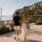 Couple walking hand in hand beside a glass padel court at a Mediterranean coastal resort